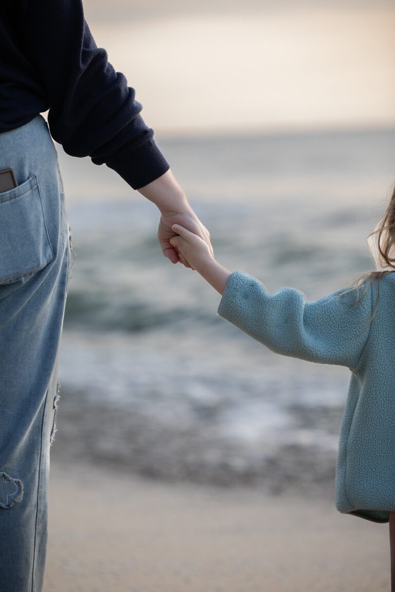 Kind bei Mama an der Hand am Strand